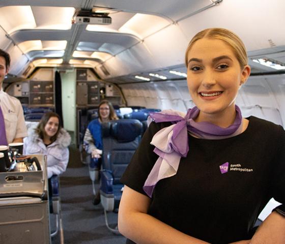 Image of Aviation Cabin Crew Students inside the aero plane with 2 passengers in their seats