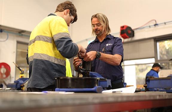 Lecturer assisting a student in automotive workshop 